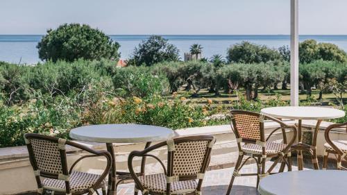 a patio with tables and chairs and a view of the ocean at MClub Alicudi in Sciacca
