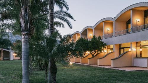 a building with palm trees in front of it at MClub Alicudi in Sciacca