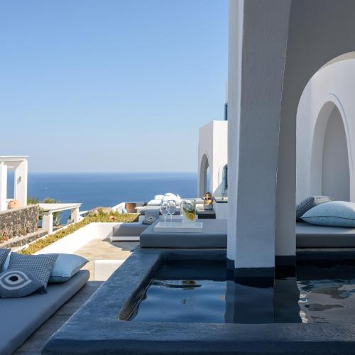 a pool on the side of a house with the ocean at Kalestesia Suites in Akrotiri