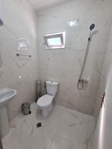 a white bathroom with a toilet and a sink at Бунгала Калина - Нестинарка in Tsarevo