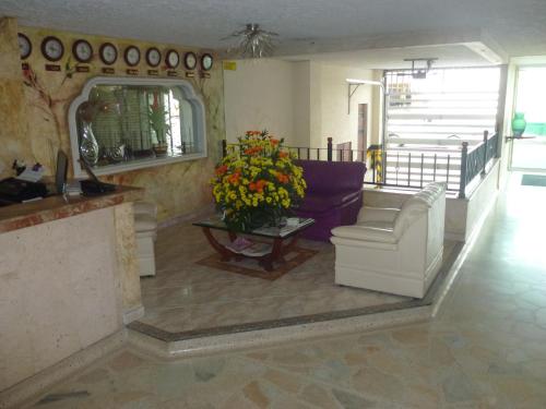 a living room with a couch and a table with flowers at Hotel San Nicolas in Bucaramanga