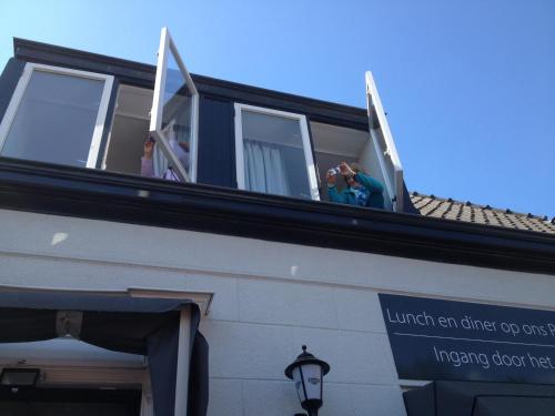 two people taking pictures from a window of a building at Bed & Breakfast De Vier Seizoenen in Lisse