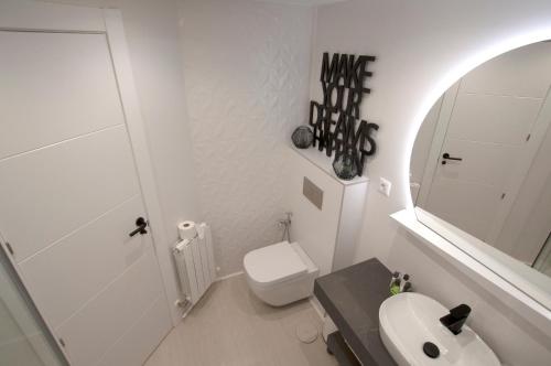 a white bathroom with a toilet and a sink at Black and White Suitte "Plaza" in Noja