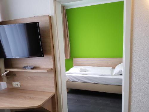 a bedroom with a green wall and a bed with a television at Hotel Citymaxx in Rostock