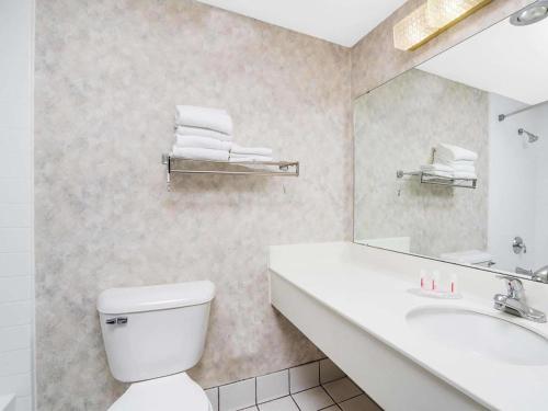 ein Badezimmer mit einem WC, einem Waschbecken und einem Spiegel in der Unterkunft Norwood Inn & Suites La Crosse in La Crosse