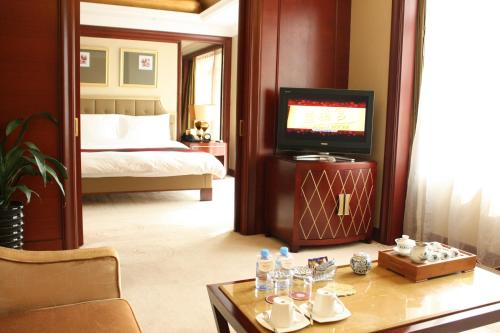 a hotel room with a bed and a television and a table at Dynasty International Hotel Dalian in Jinzhou
