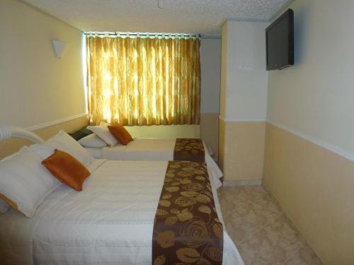 a hotel room with two beds and a television at Hotel San Nicolas in Bucaramanga