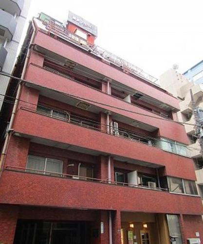 a tall red brick building with a balcony at HAMAMATSUCHO Mansion #2DK# Minato-ku in Tokyo