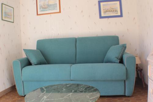 ein blaues Sofa im Wohnzimmer mit einem Tisch in der Unterkunft Gîte des Belles Fontaines in Neung-sur-Beuvron