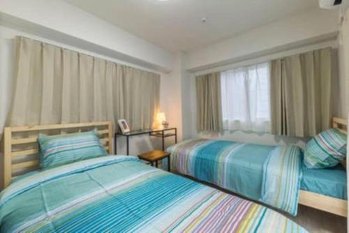a bedroom with two beds and a window at HAMAMATSUCHO! 5 mins to subway sta with FREE-WIFI in Tokyo