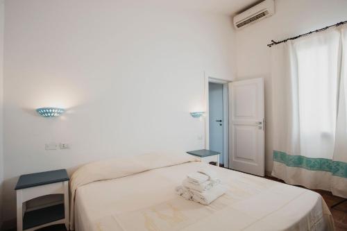 a white bedroom with a bed and a window at Resort Fior di Sardegna in Posada