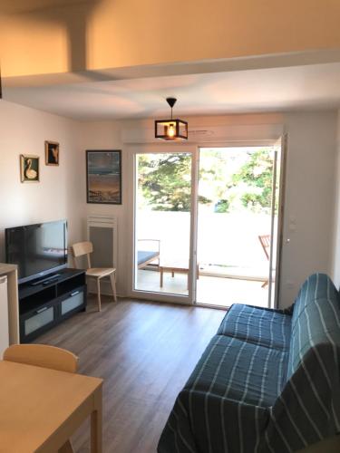 a living room with a couch and a sliding glass door at Au cœur de Lacanau Océan Appartement neuf avec parking in Lacanau-Océan