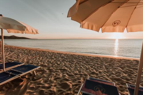 a beach with an umbrella and a chair and a table at Resort Fior di Sardegna in Posada
