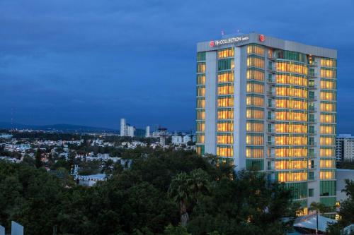a tall building with lights on in a city at NH Collection Guadalajara Providencia in Guadalajara