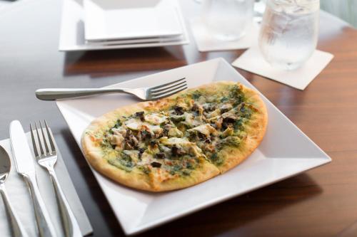 a pizza sitting on a white plate on a table at Hyatt House Dallas / Frisco in Frisco