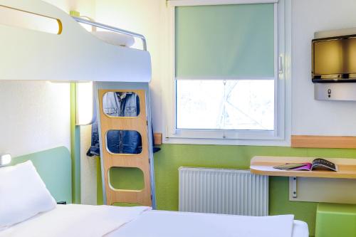 a room with a bed and a desk and a window at ibis budget Paris Porte de Vanves in Vanves