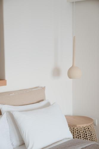 a white bed with white pillows and a table at Mon Signor in Kamari