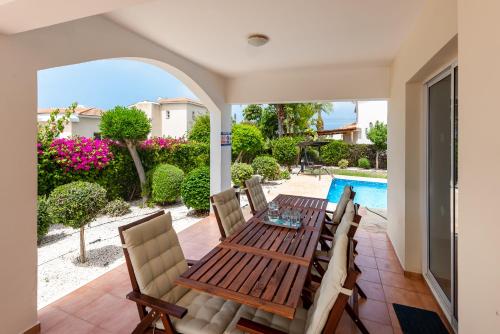 a dining room with a table and chairs and a swimming pool at Villa Alysia by Ezoria Villas in Coral Bay