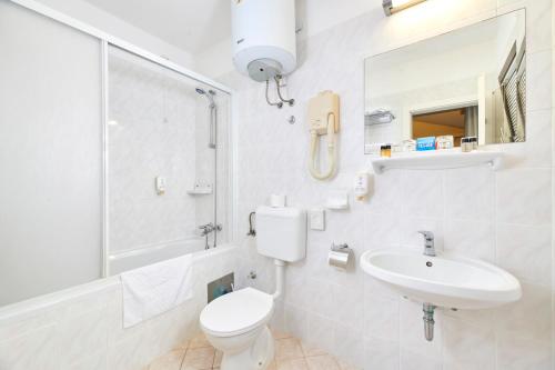 La salle de bains blanche est pourvue de toilettes et d'un lavabo. dans l'établissement Village Galijot Plava Laguna, à Poreč
