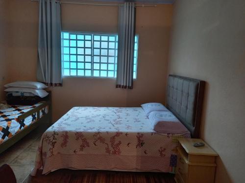 ein kleines Schlafzimmer mit einem Bett und einem Fenster in der Unterkunft Recanto Flor de lis in Gonçalves
