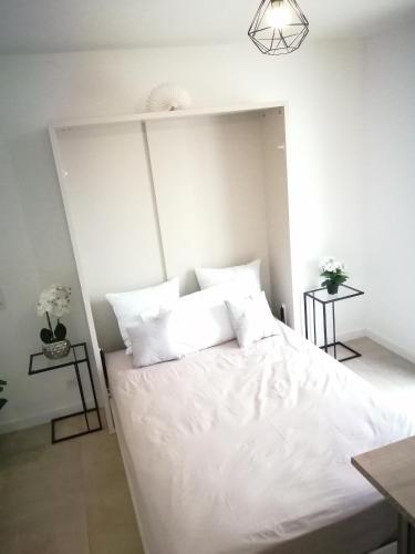 une chambre blanche avec un grand lit avec des oreillers blancs dans l'établissement Studio neuf Paris La Défense Metro 15 Rueil - Suresnes - Mont Valerien, à Rueil-Malmaison