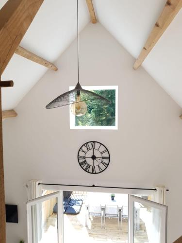 a clock hanging from the ceiling of a room at Les Deux Lacs - Stunning Gite, with private swimming pool and 2.75 acre fishing lake in La Chapelle-Verlaine