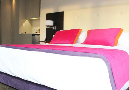 a large bed with two pink pillows on it at Bulnes Eco Suites in Buenos Aires