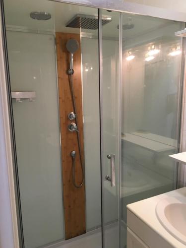 La salle de bains est pourvue d'une douche avec une porte en verre. dans l'établissement Maison de caractère à 5mn à pied de la plage, à Mesquer