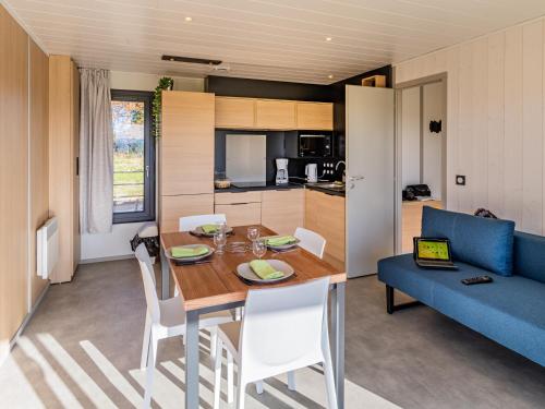 une cuisine et une salle à manger avec une table et un canapé bleu dans l'établissement Les Quatre Vents, à Courpière