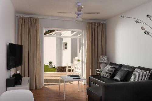 a living room with a black couch and a table at Villas New Lanzasuites in Playa Blanca
