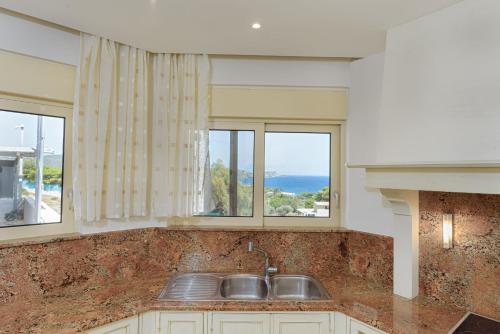 a kitchen with a sink and two windows at Cape Sounio Villa in Sounio