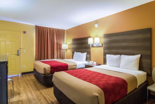 una camera d'albergo con due letti con lenzuola rosse di Econo Lodge Kingsland a Kingsland