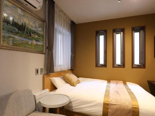 a bedroom with a bed and a chair and windows at GRAND BASE Hakataminami in Fukuoka