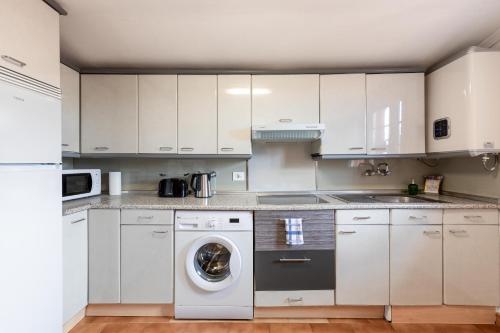 a kitchen with white cabinets and a washing machine at Zumaiako Txapitula - BasKey rentals in Zumaia