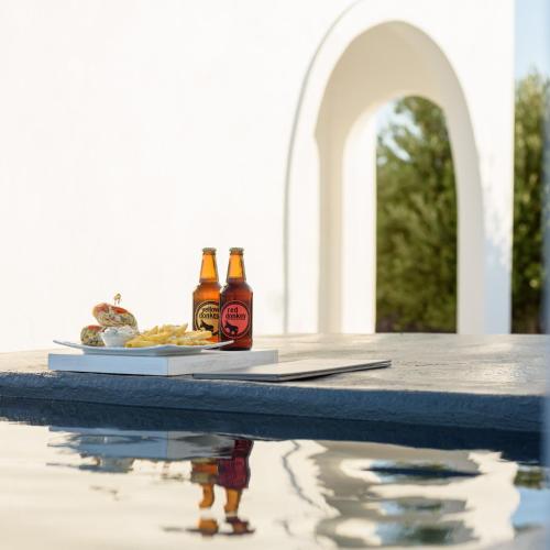 a table with two bottles of beer and a plate of food at Kalestesia Suites in Akrotiri