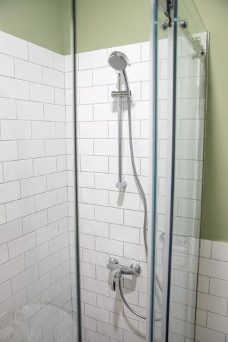 a shower in a bathroom with white tiles at Seven cafe & hotel in Pogradec