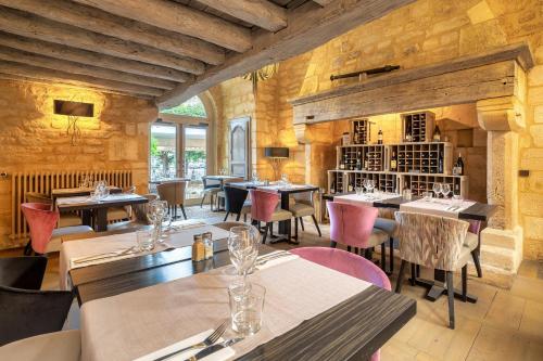 un restaurante con mesas y sillas en una habitación en Hôtel La Couleuvrine Sarlat Centre Ville en Sarlat-la-Canéda