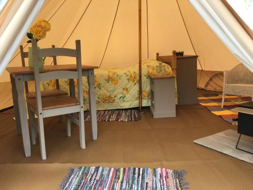 a room with a table and a chair in a tent at Glamping at The Homestead - Ensuite bell tent in Hereford