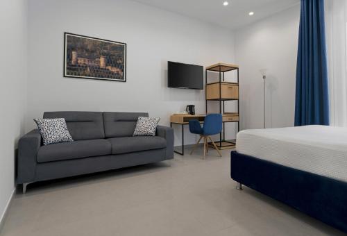 1 dormitorio con sofá, cama y escritorio en HSuites Luxury B&B, en Castellammare di Stabia
