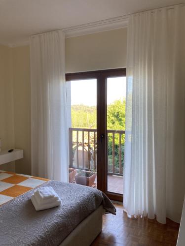 a bedroom with a bed and a balcony with a sliding glass door at Casa do Tavares in Carvalhais