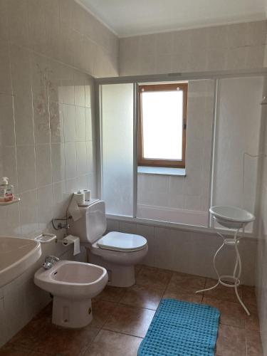 a bathroom with a toilet and a tub and a sink at Casa do Tavares in Carvalhais