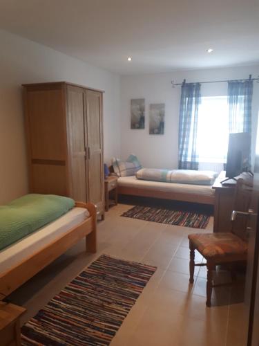 1 dormitorio con 2 camas, ventana y sofá en Siebler Übernachtungen am Bauernhof, en Wolnzach