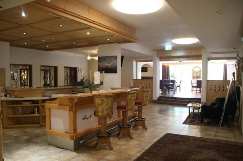 Großes Zimmer mit einer Theke und Stühlen. in der Unterkunft Gasthof zum Löwen in Aschau