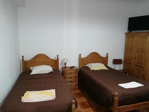 two beds in a room with a tv and a dresser at Hospedaria D. Fernando in Viseu
