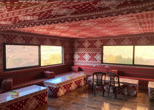 a room with red walls and windows with tables and chairs at Desert Mars Camp & Tours in Wadi Rum