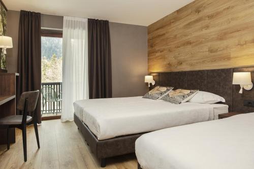 a hotel room with two beds and a balcony at Hotel Canin in Sella Nevea