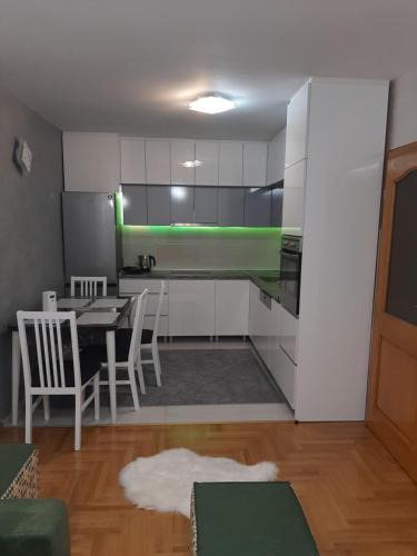 a kitchen with white cabinets and a table and chairs at Apartman Ruža in Vogošća