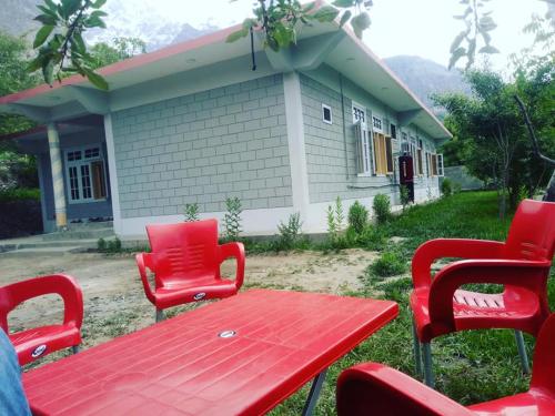 una mesa roja y sillas frente a una casa en Hunza Regency Inn, en Hunza