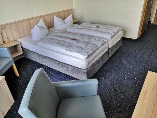 a bed in a small room with a chair and a bedskirtspectspectspects at Rügen-Hotel in Sassnitz
