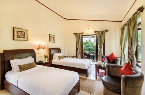 a hotel room with two beds and a chair at The Riverwood Forest Retreat Dooars - fully vaccinated staff in Neorā Nadī